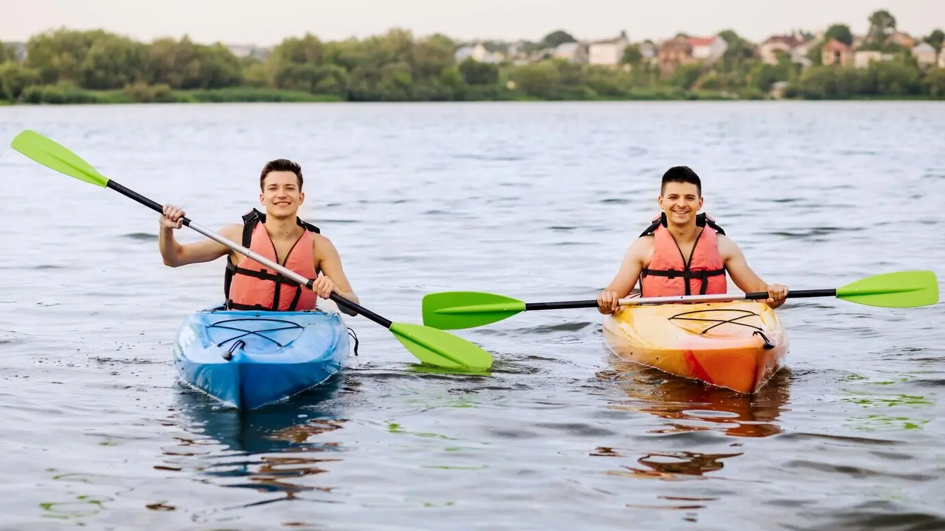 Two happy men kayaking on a lake.