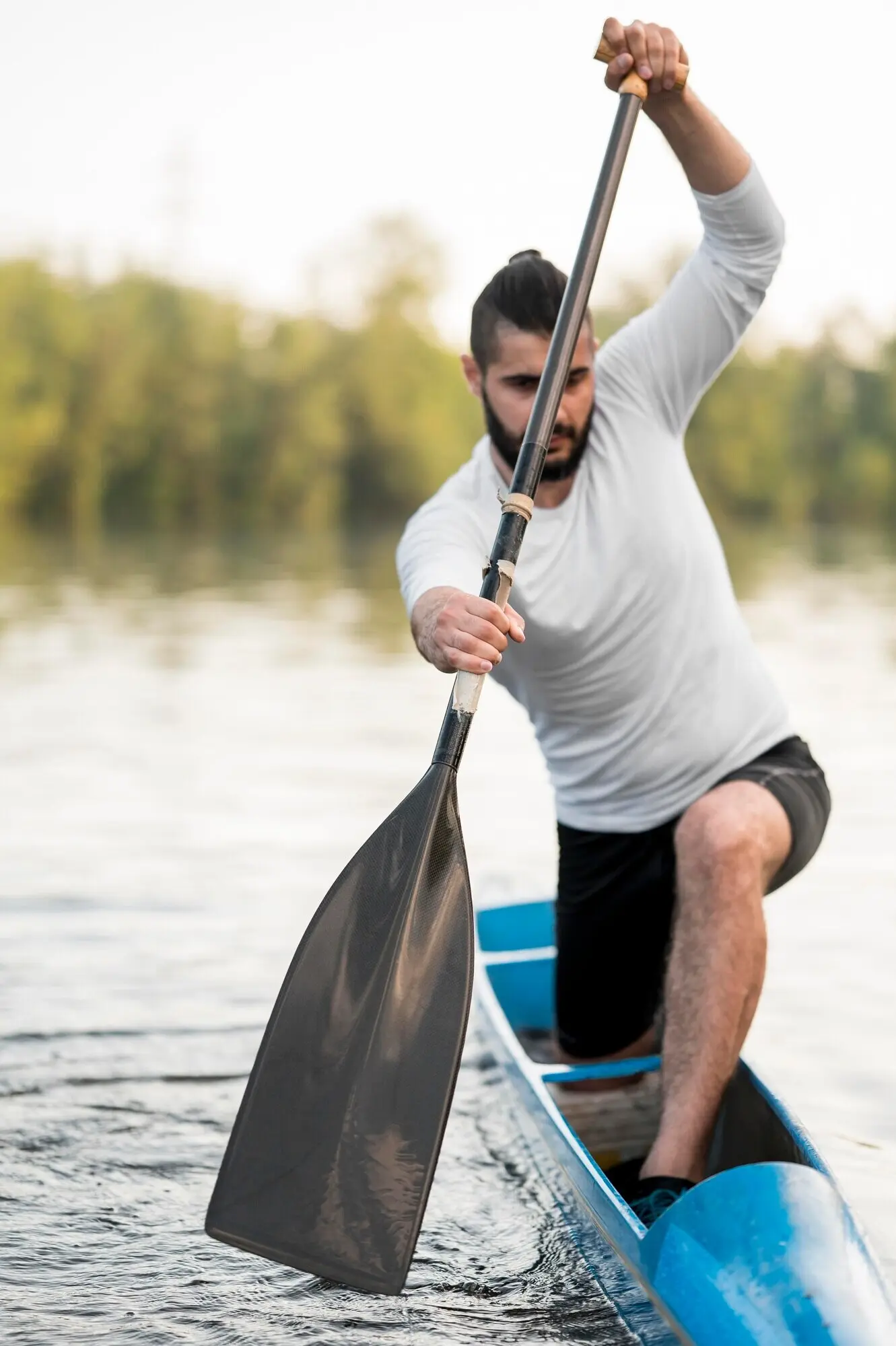 A long shot of a man rowing with an oar.